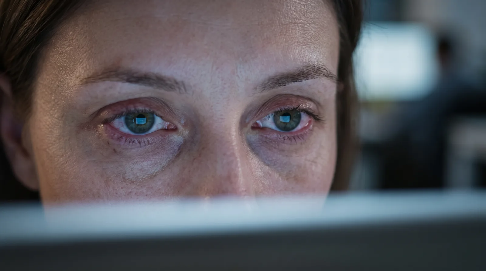 A close view of tired, strained eyes lit by the glow of a screen