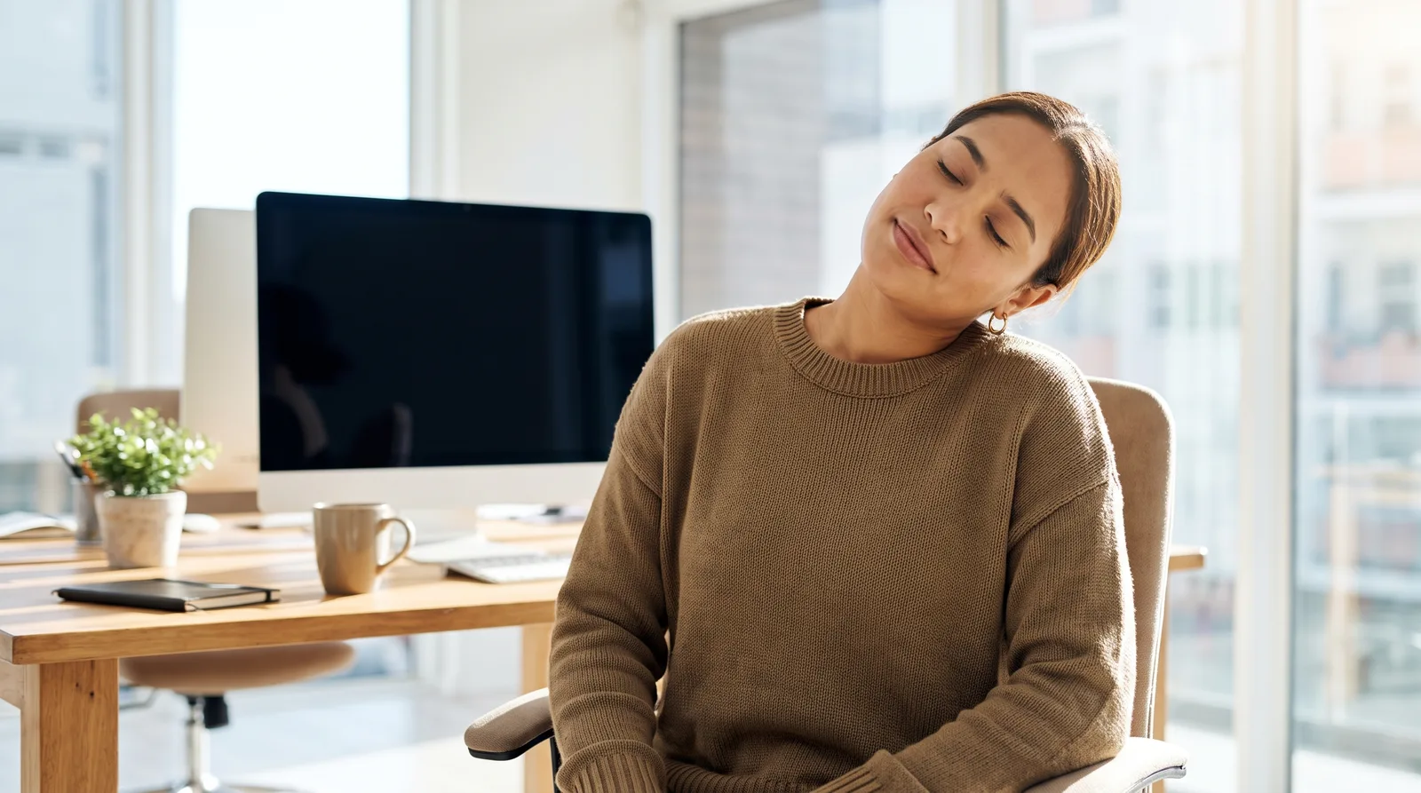 A person at a desk doing a gentle, controlled neck movement during a work break