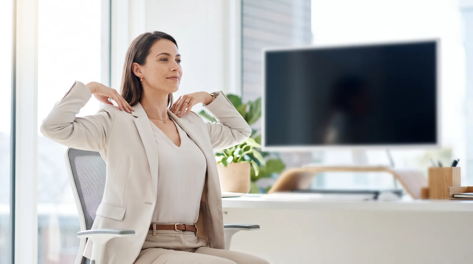 A person at a desk squeezing their shoulder blades together in a gentle rowing motion